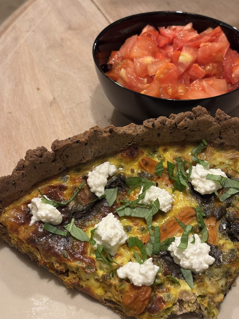 Part de quiche aux légumes et cottage cheese, accompagnée d'une salade de tomates
